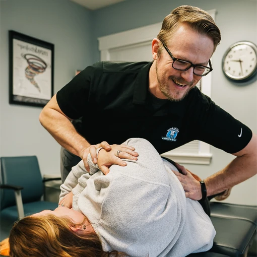 Dr. Zachary Zdrada smiling while adjusting a patient's back